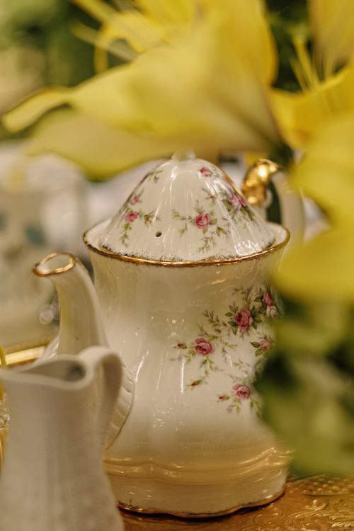 Free Beautiful vintage porcelain teapot with floral patterns surrounded by yellow flowers, perfect for tea time themes. Stock Photo