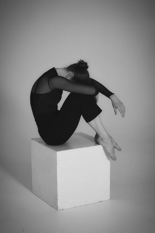 Free Artistic black and white photo of a woman sitting gracefully on a cube, conveying elegance. Stock Photo