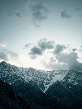A stunning view of snow-covered mountains under a dramatic twilight sky.