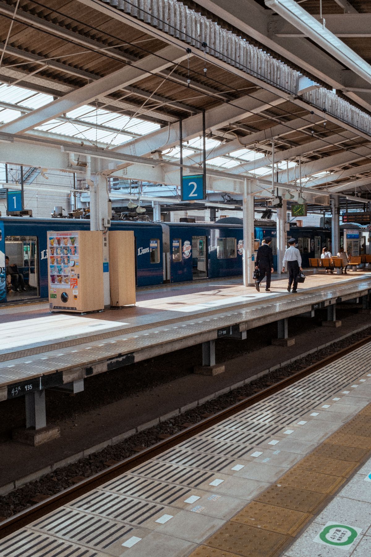 Japanese train station platform with tracks and passengers waiting to board