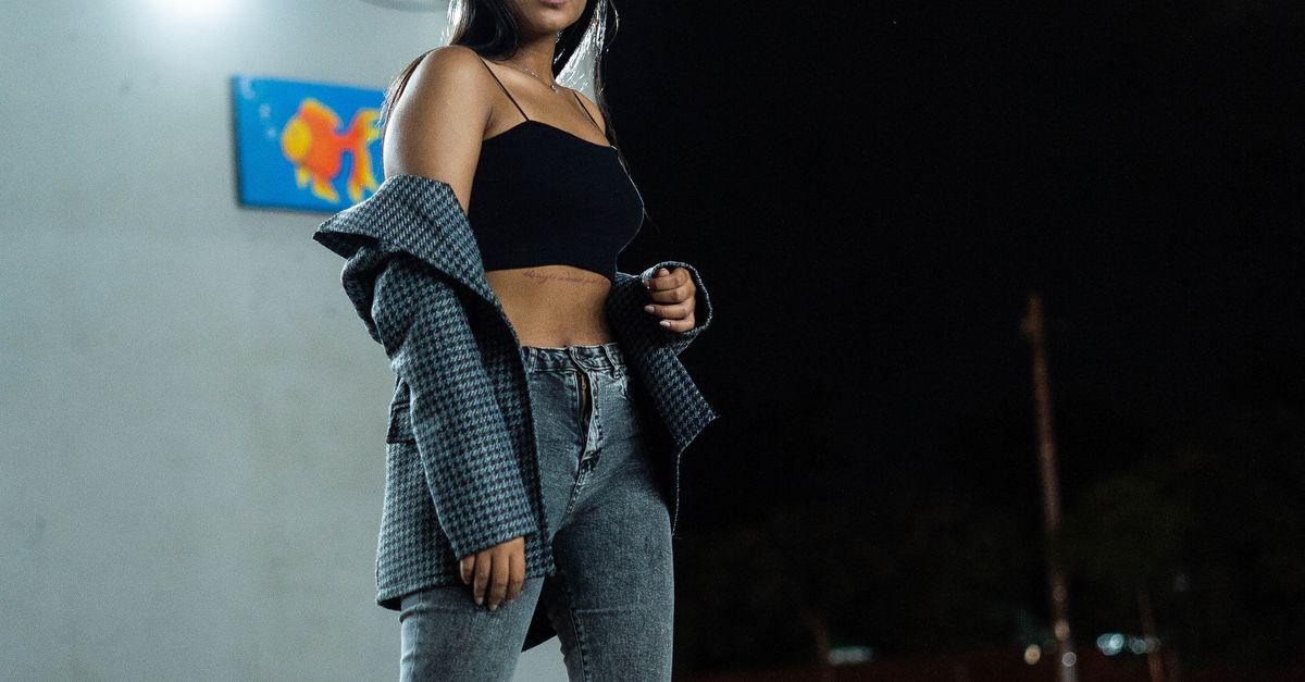 Woman in dark straight-leg jeans with a black bodysuit and heels
