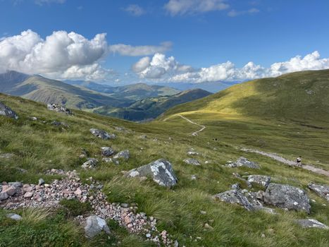 A breathtaking view of a mountainous landscape under a bright blue sky with fluffy clouds.