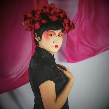A striking portrait of a woman with a floral crown, set against vibrant pink drapery.