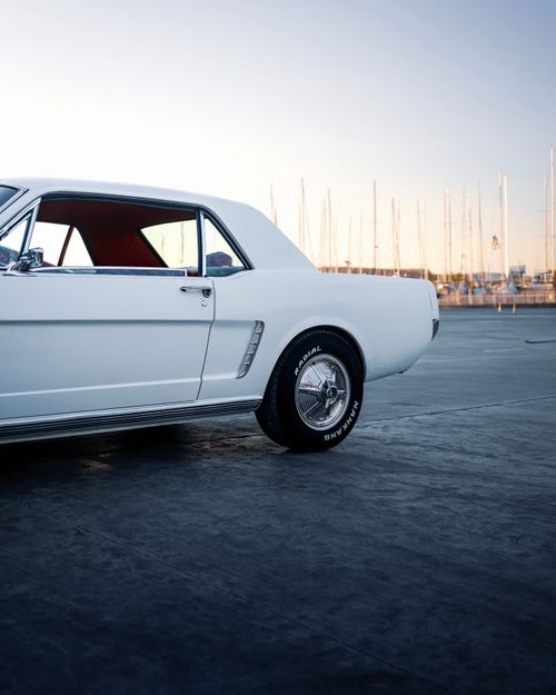 Free Classic white Mustang parked at İzmir Marina during sunset, highlighting its vintage design. Stock Photo