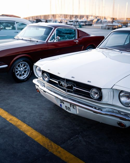 Free Vintage Ford Mustang cars parked by the marina in İzmir, Türkiye during sunset. Stock Photo