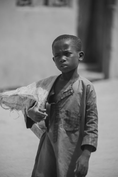 Free Black and white portrait of a young boy holding a net outdoors, wearing traditional attire. Stock Photo