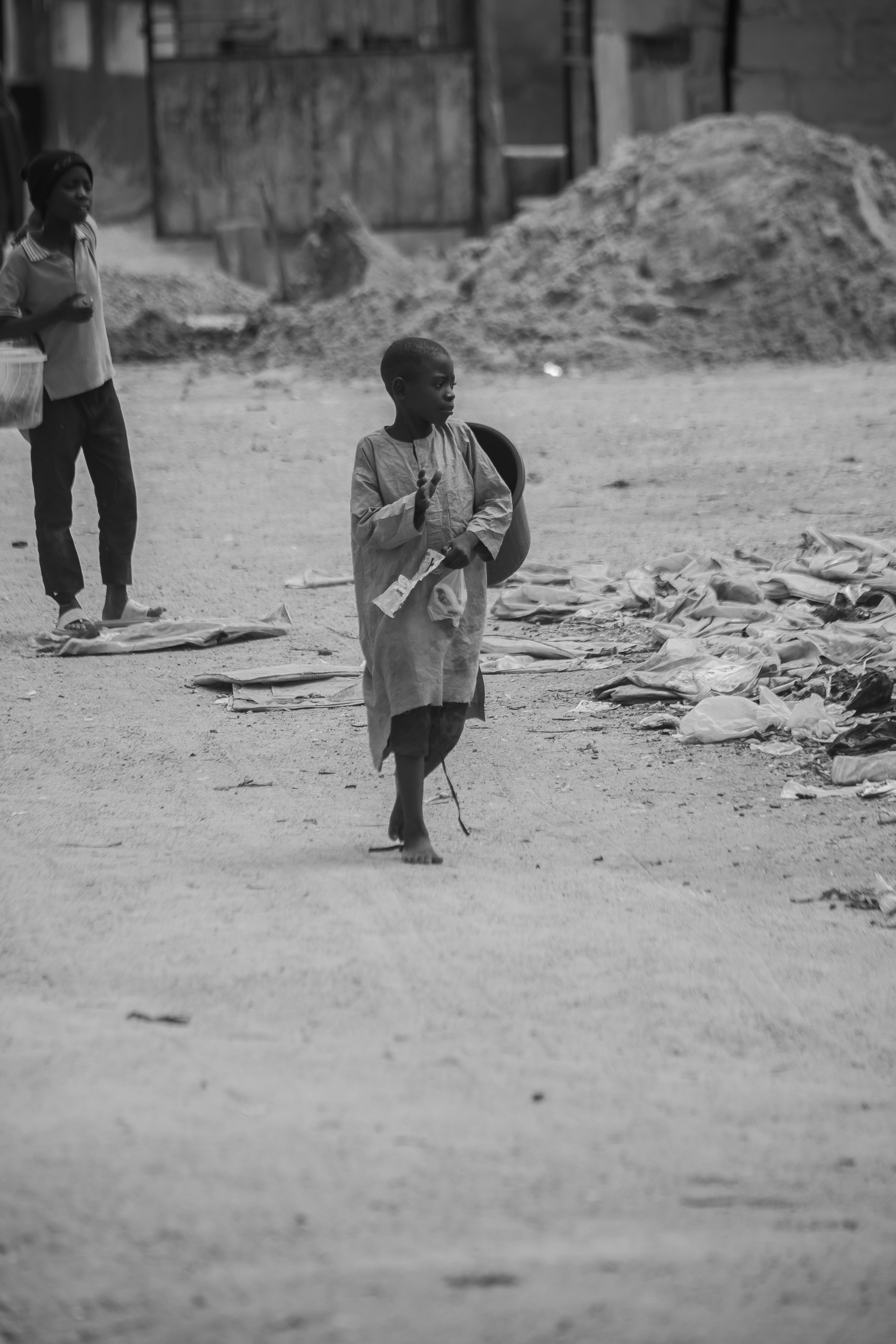 Black and white photo of children walking on a dusty street.