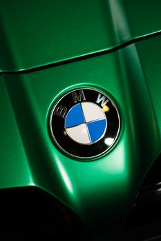 Close-up shot of a BMW logo on a vibrant green hood, capturing automotive elegance. 33056818