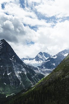 Beautiful mountain landscape with snow-capped peaks and dramatic clouds.