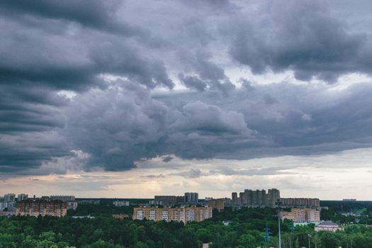 Aerial view of a cityscape under dramatic cloudy sky showcasing urban architecture.