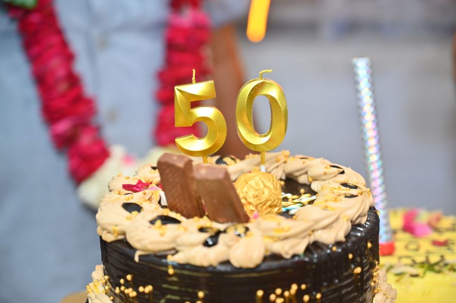 Elegant chocolate cake with golden 50th anniversary candles and decorations.
