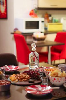 A warm and inviting indoor dining scene with snacks and drinks on a table, surrounded by vibrant red chairs.