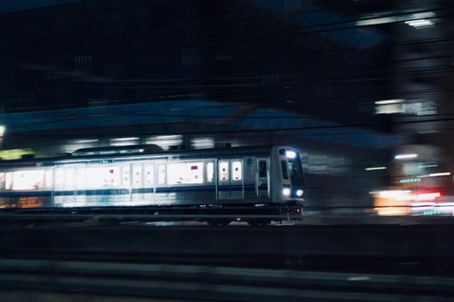 Free Blurry cityscape with a train captured at night, showcasing speed and urban life. Stock Photo