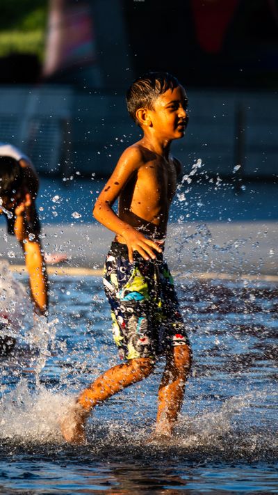 Children having fun in a water fountain during a sunny day