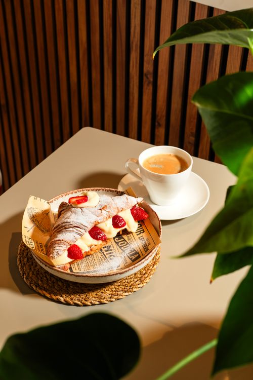 Free A delicious croissant topped with strawberries alongside a cup of coffee in cozy indoor setting. Stock Photo