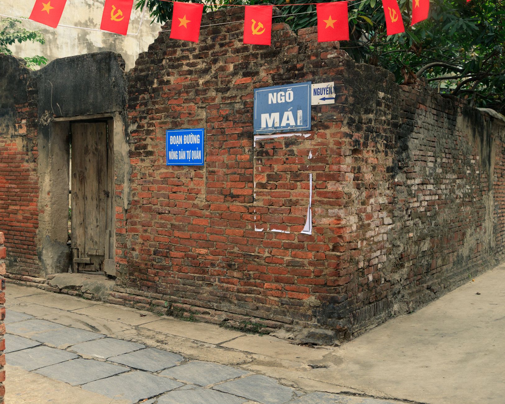 Explore the rustic charm of an old brick wall in Bắc Ninh, decorated with flags.