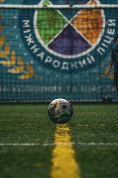 Soccer ball on a field in front of Kyiv International School backdrop, Ukraine.