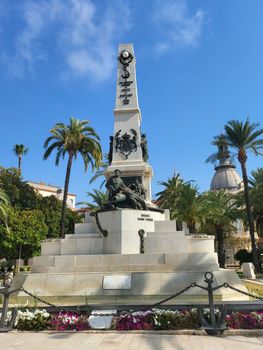 Monument surrounded by palm trees under a clear blue sky in an urban setting.