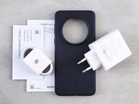 Flat lay of HONOR phone case, charger, and warranty documents on a table.