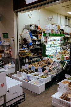 Explore a bustling Japanese market stall filled with fresh produce and local items in a vibrant indoor setting.