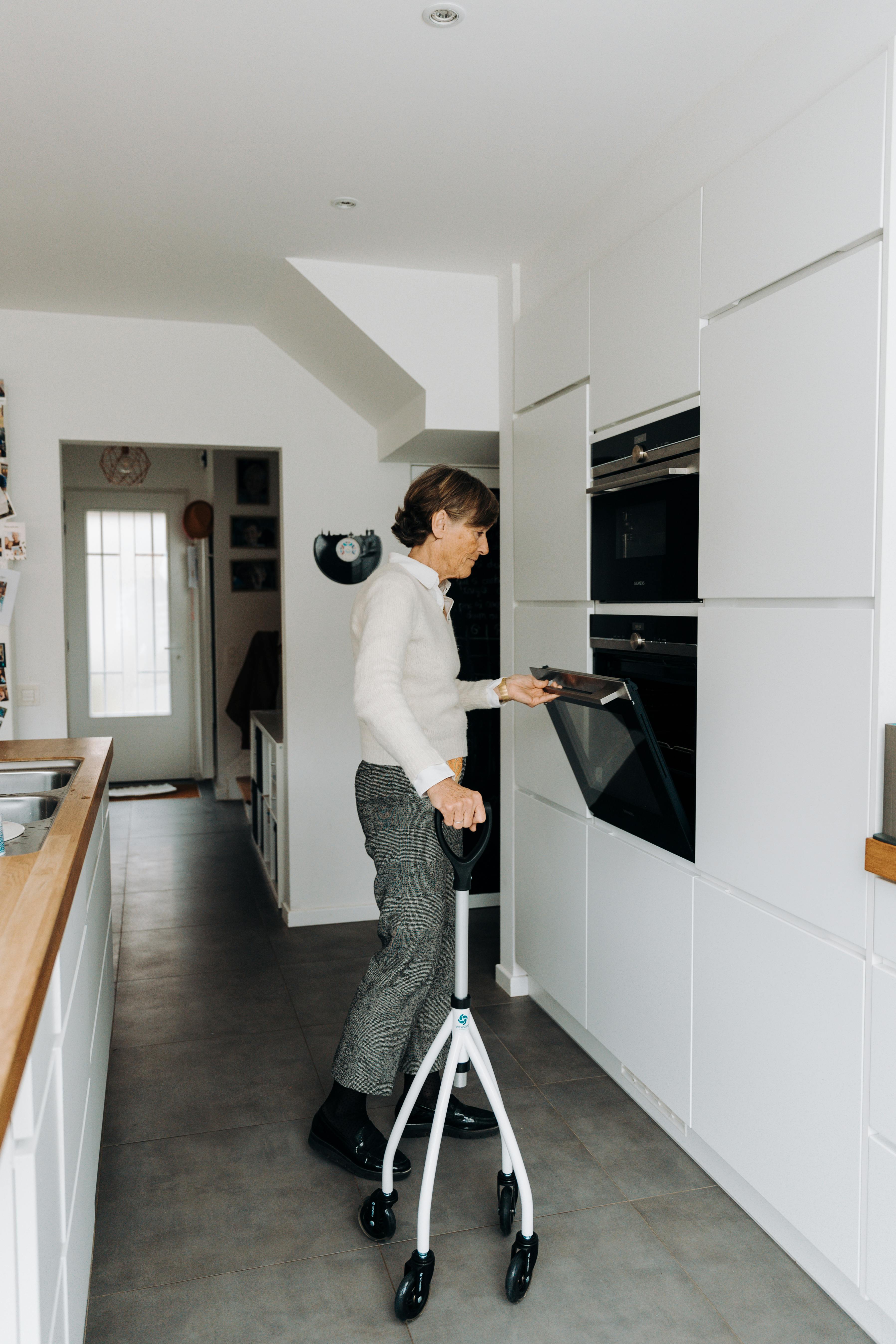 Senior woman using walker while baking in a modern kitchen, showcasing independence.