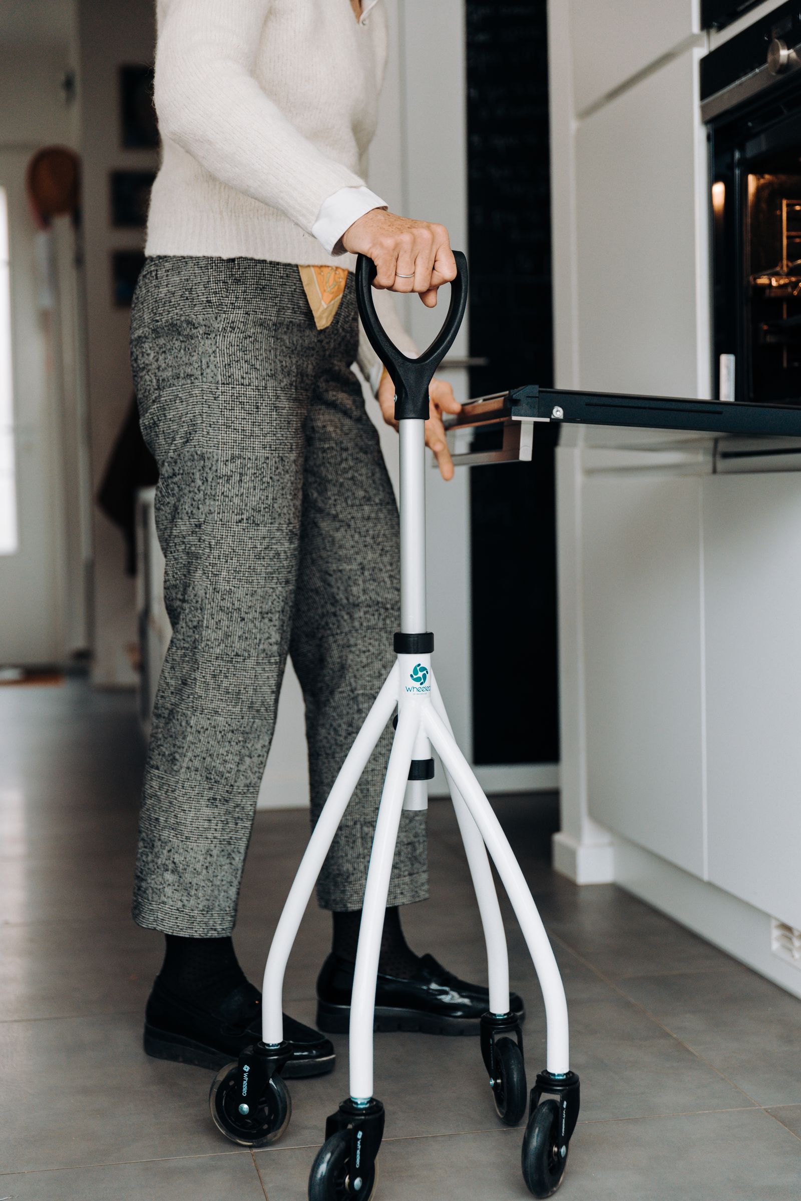 Senior adult standing with a mobility aid in a kitchen