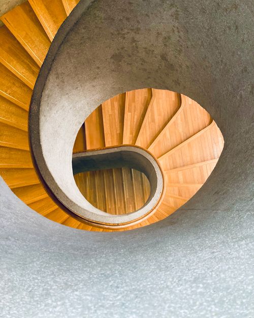 Free A mesmerizing spiral staircase with a wooden finish and artistic design, viewed from above. Stock Photo