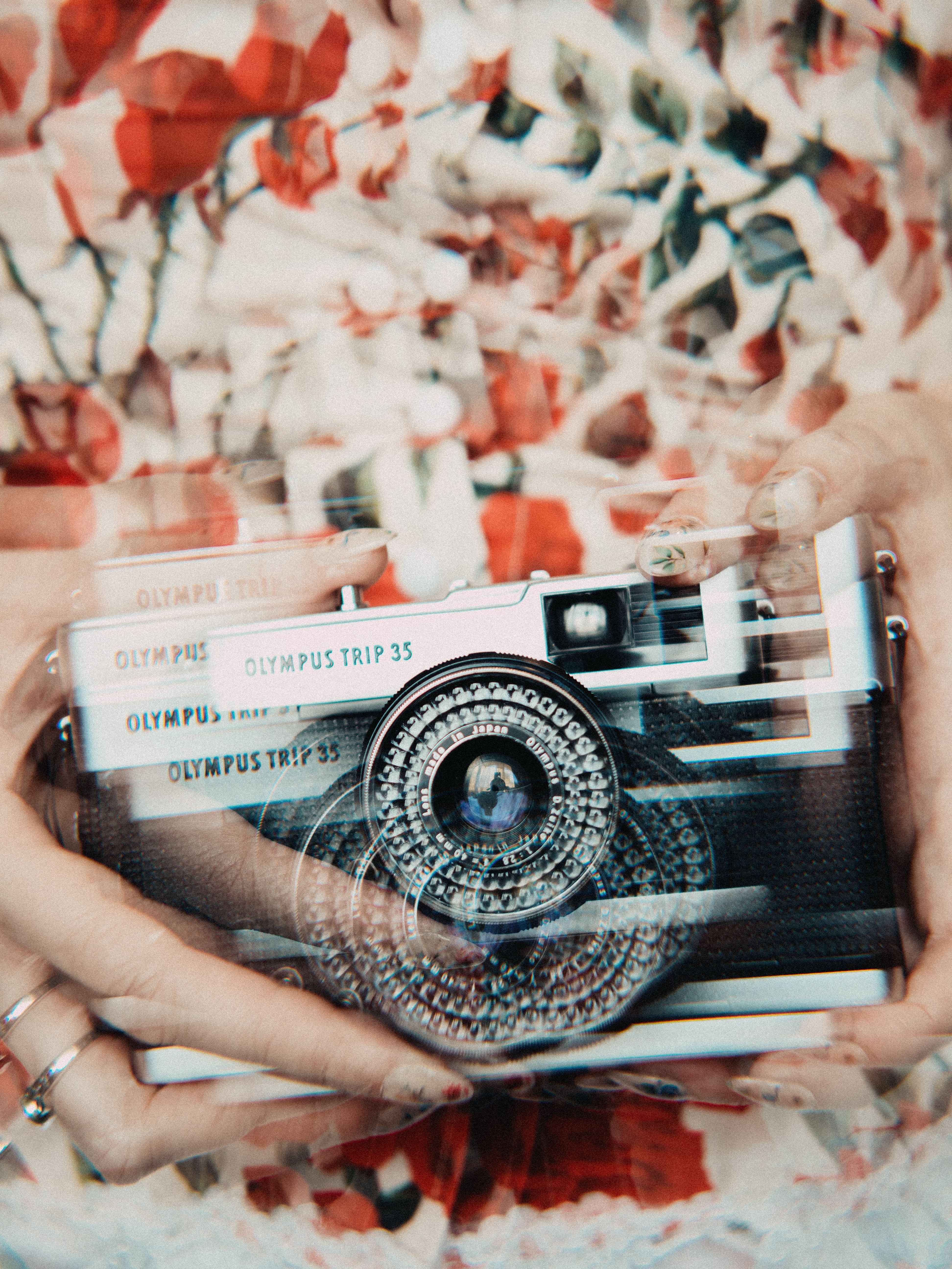 Double exposure shot of a vintage Olympus camera against a floral background.