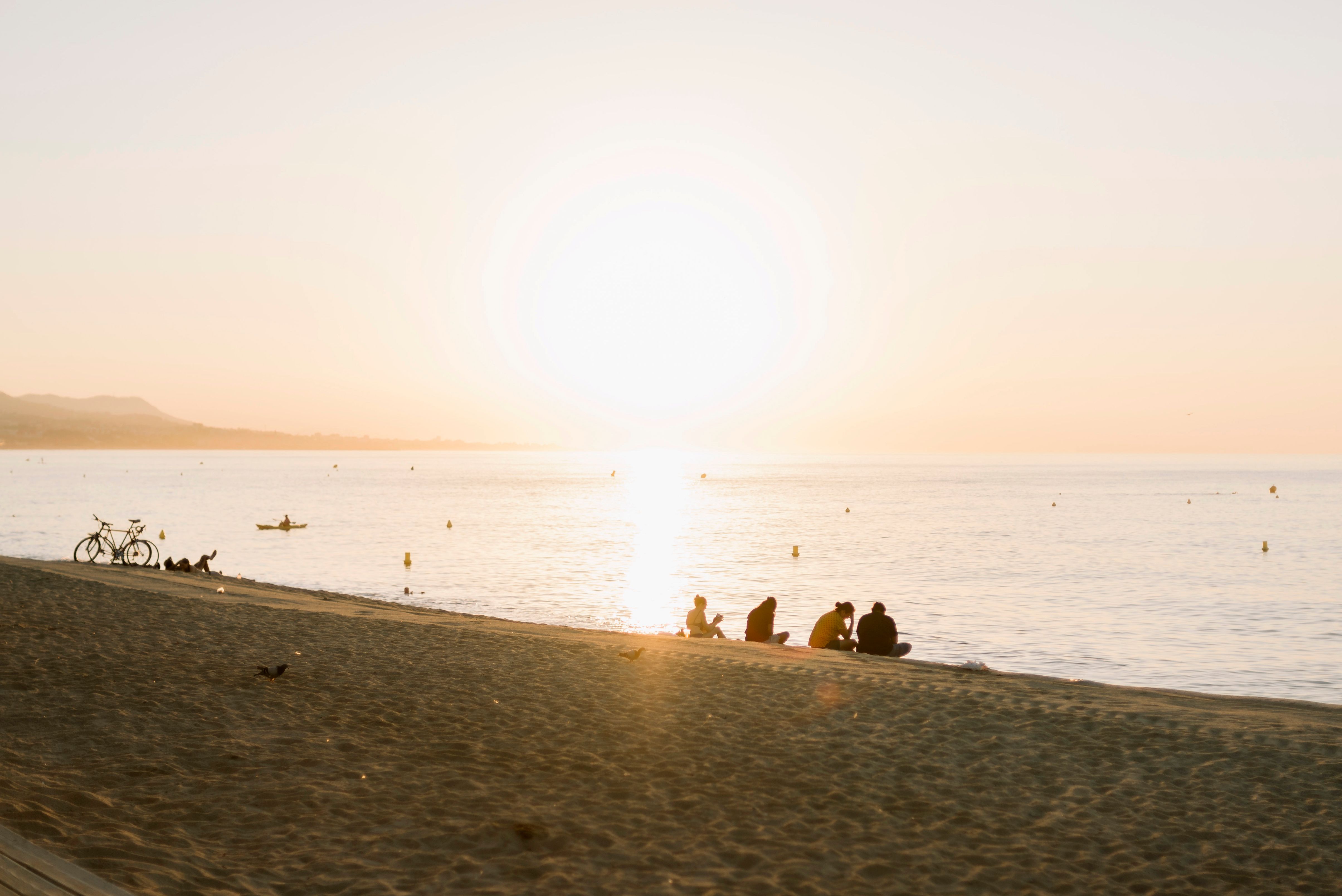Serene Beach Sunset with Silhouetted People · Free Stock Photo