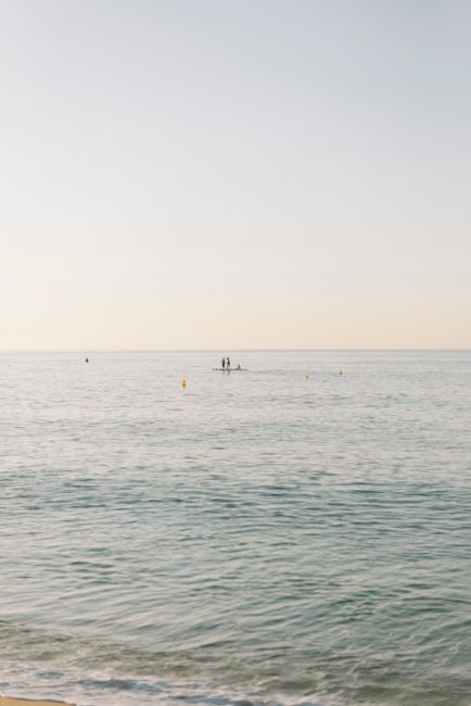 Calm ocean with paddleboarders under a serene sunset sky, perfect for peaceful moments.