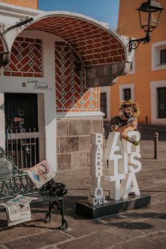 A street performer in Puebla's Barrio del Artista, posing with urban art.