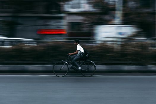 A motion blur captures a cyclist on a bustling street in Kolkata, India.