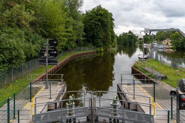 Écluse bordée de verdure avec des bateaux amarrés sous un ciel nuageux