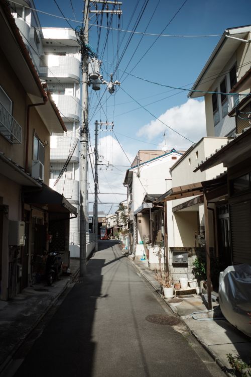 Free A serene view of a traditional residential street in Kyoto, Japan, under a clear blue sky. Stock Photo