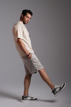 Side profile of a relaxed man in beige outfit posing in a studio setting.