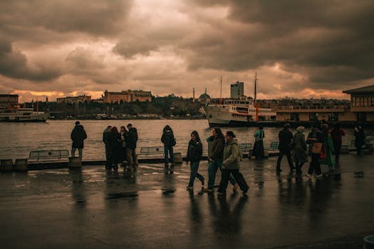 A moody urban scene with people on a rainy day in Istanbul, Türkiye, featuring a ferry on the Bosphorus.