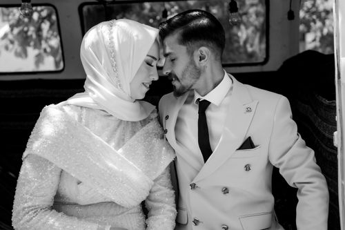 Free A romantic black and white photo of a bride and groom leaning close in an intimate wedding setting. Stock Photo