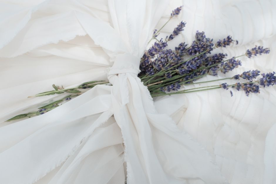 A delicate bouquet of lavender rests elegantly on soft, white fabric, creating a peaceful and serene composition.
