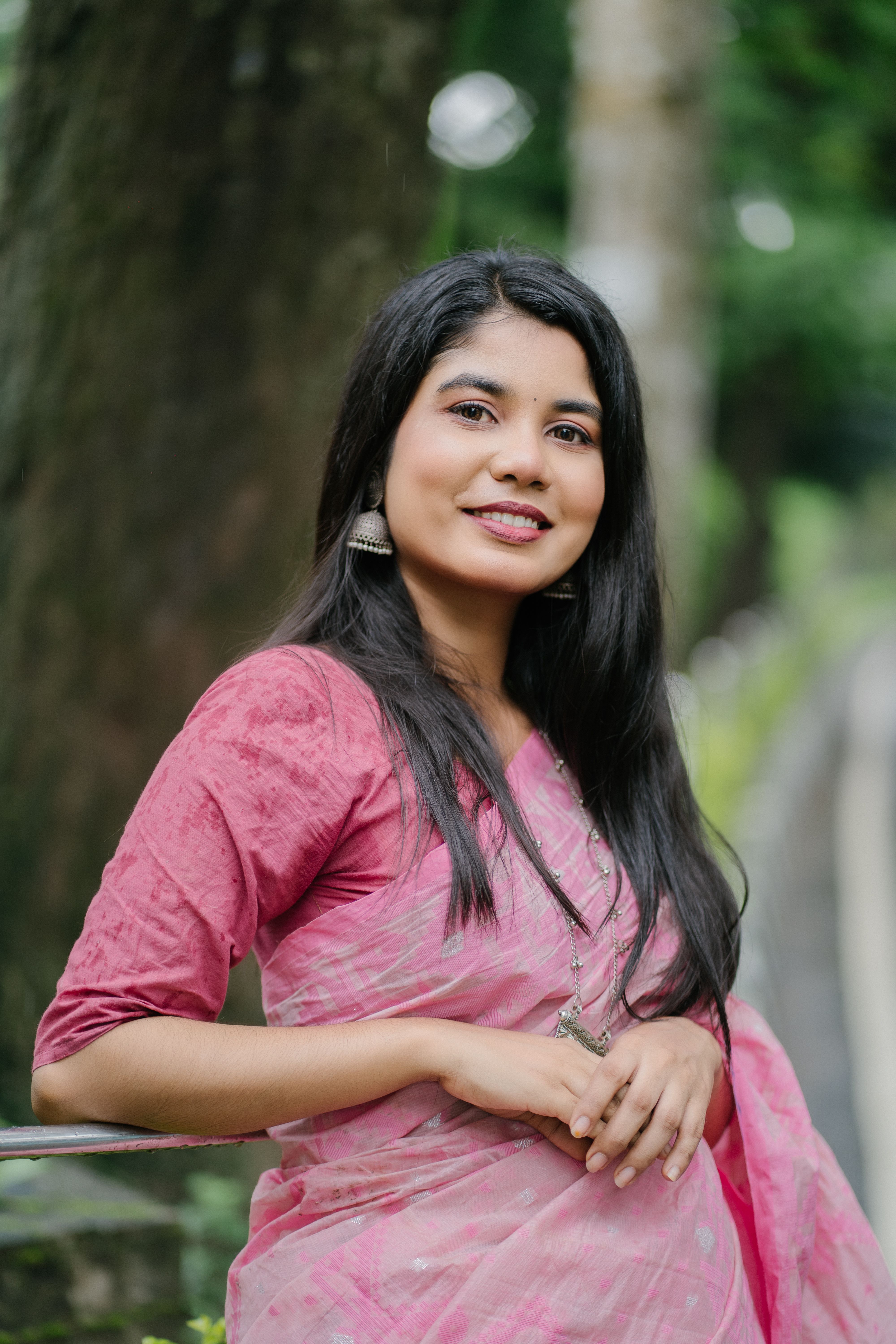 Portrait of a smiling woman in a pink sari with natural background.