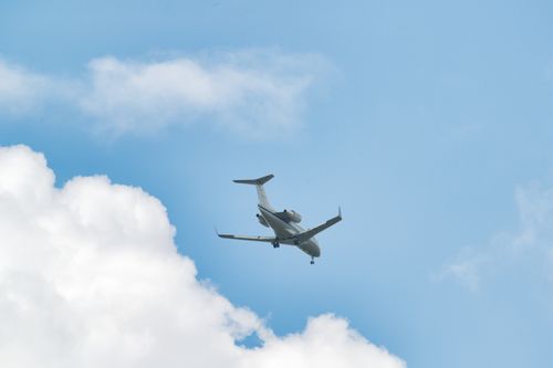 Free An airplane soaring above clouds in a clear blue sky, captured during daytime. Stock Photo