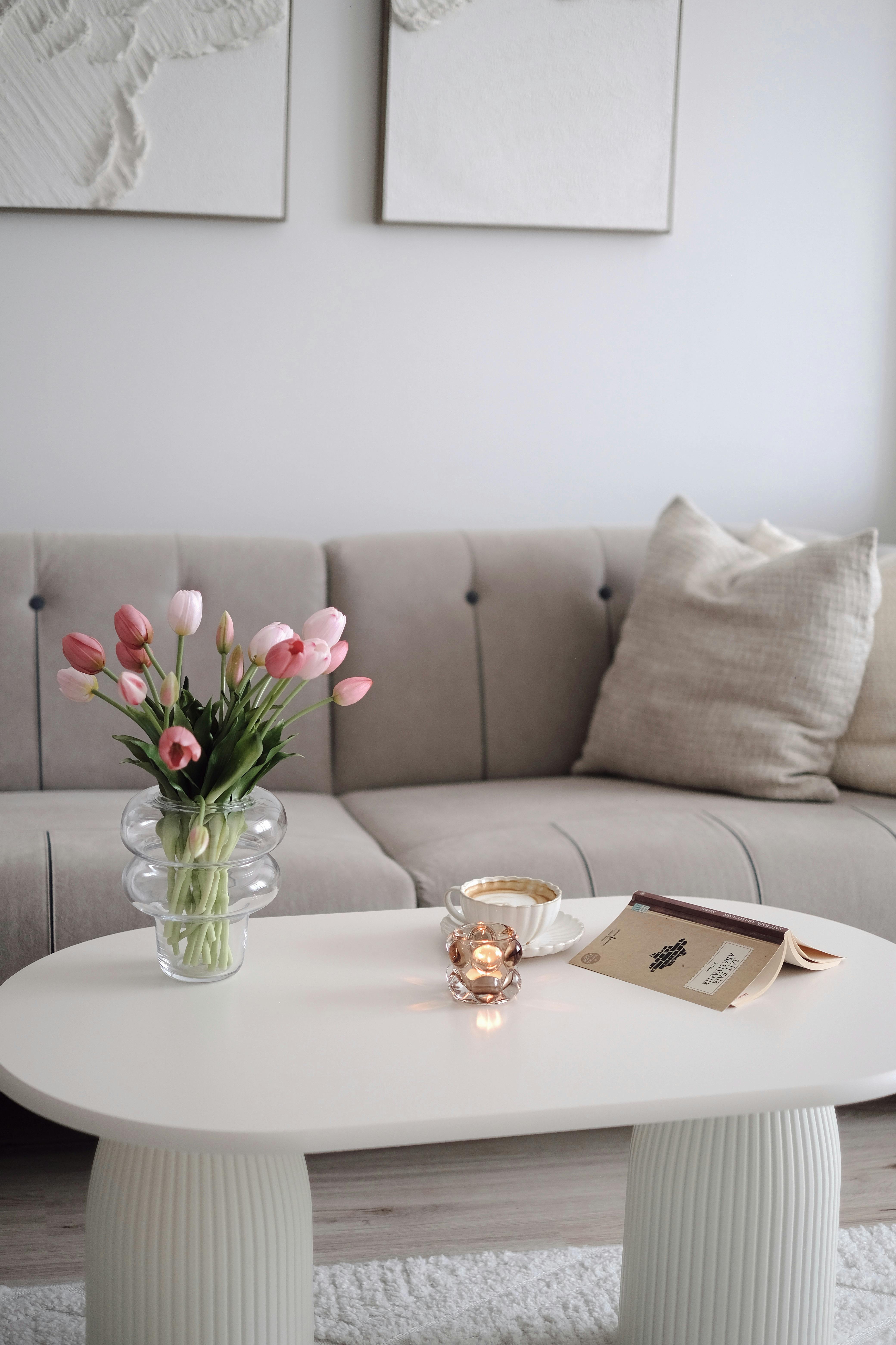 Stylish living room with tulips on a coffee table, soft couch, and decorative elements.