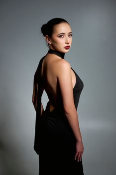 Elegant portrait of a woman in a striking backless black dress with dramatic lighting.