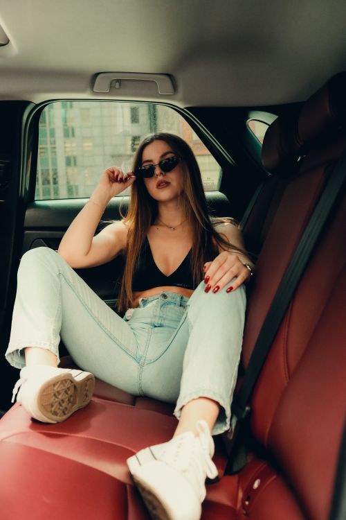Free Stylish young woman in sunglasses lounging in a car, embodying urban fashion and lifestyle. Stock Photo