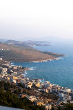 A breathtaking view of Sarandë, Albania's coastline during golden hour, highlighting cityscape and sea.