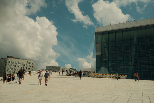 A sunny day at Oslo Opera House showcasing its modern architecture and visiting tourists.