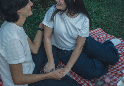Free Two young adults enjoying a picnic on a grassy field, showcasing love and relaxation. Stock Photo