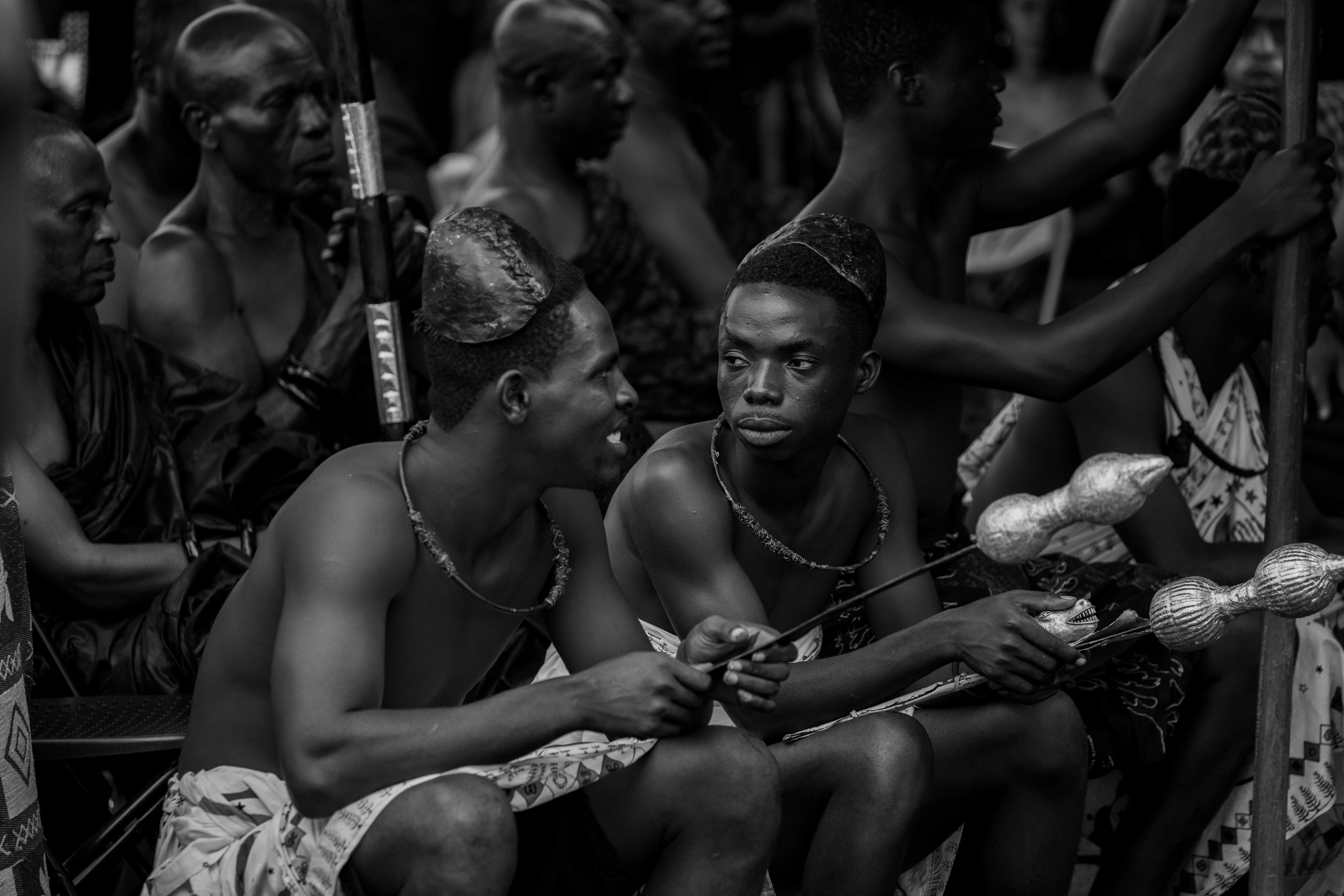 Black and white photo capturing a traditional cultural ceremony with men in traditional attire.