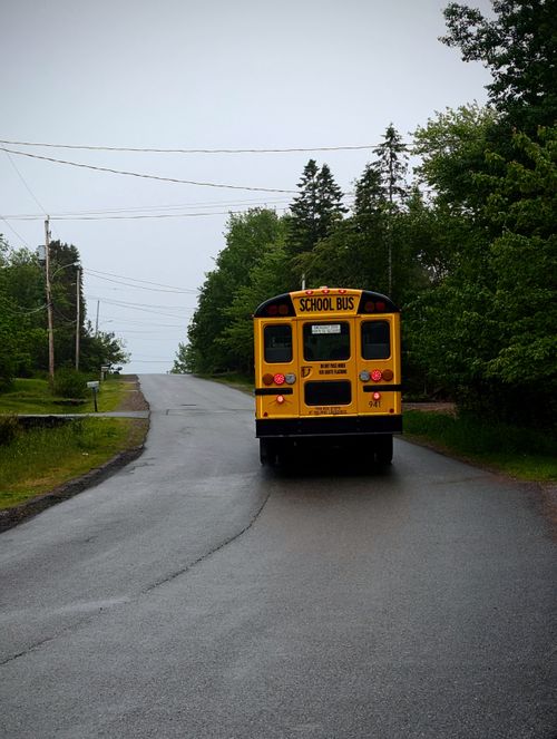 Free A yellow school bus travels down a deserted rural road in Truro, Nova Scotia, Canada. Stock Photo