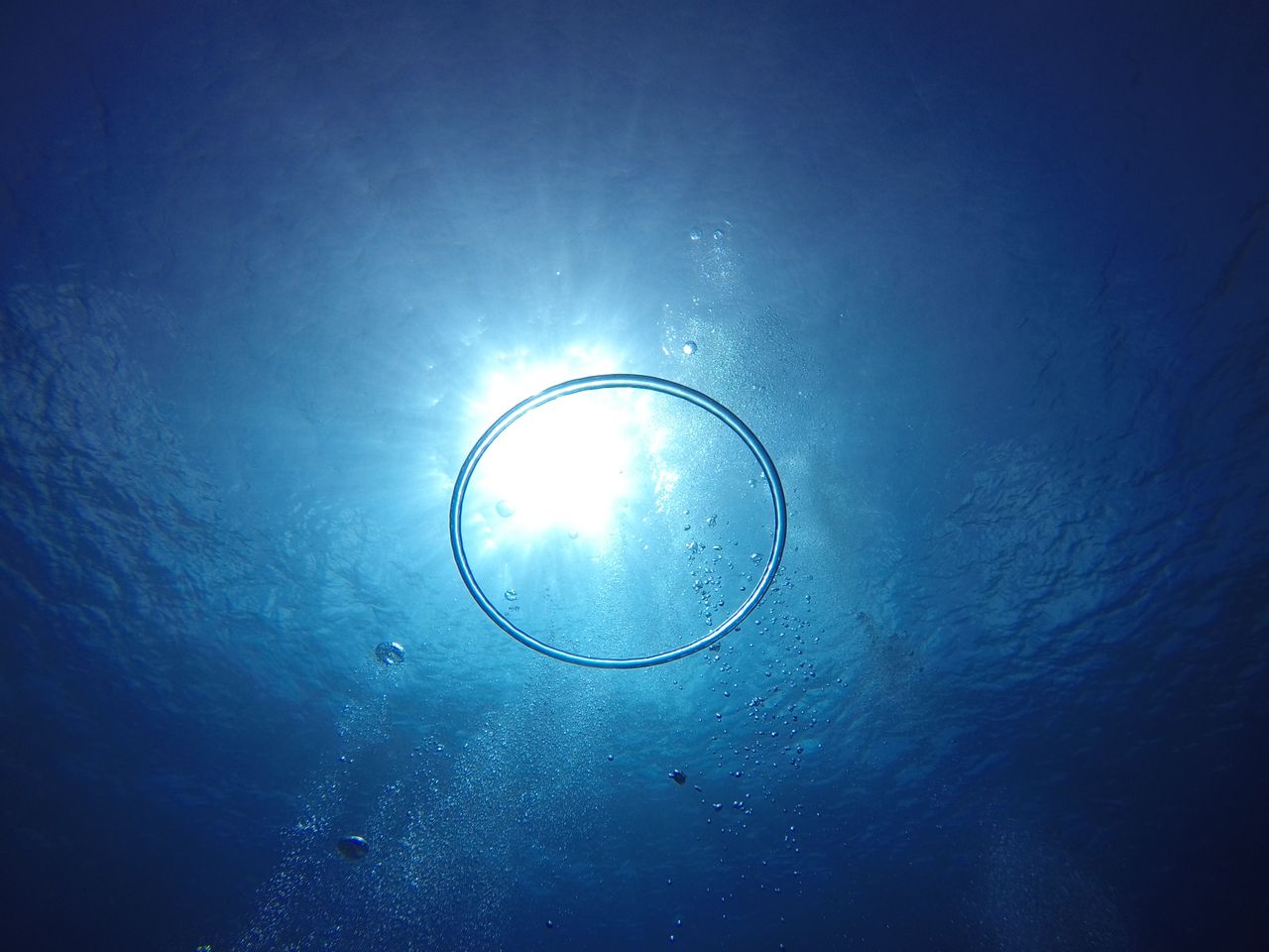 a captivating underwater view of a bubble ring with sunlight shining t