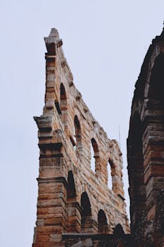 Detailed view of the Verona Arena's ancient stone arches against a clear sky.